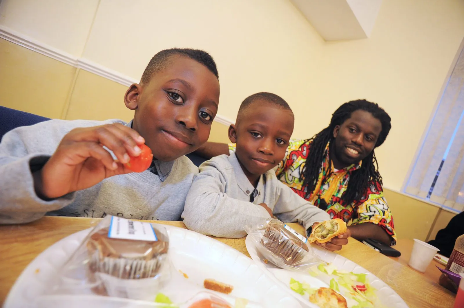 Children and a parent enjoying cake at a MEG community party